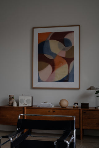 Loft living room console with sculptural objects, candle and incense, books, and an oversized abstract painting